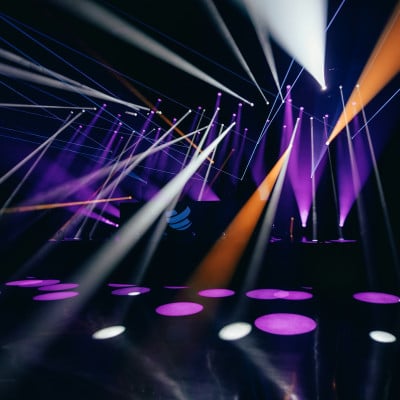 Purple, orange, and white stage lights crossing a dance floor