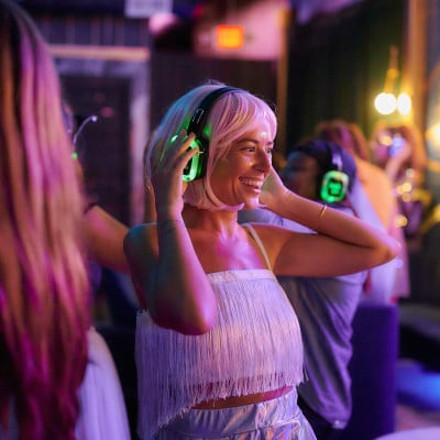 Person dancing with illuminated headphones at a silent disco