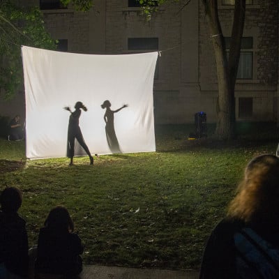 Audience watching two silhouetted performers during Small Works at LUMA