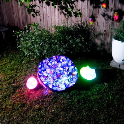 Glowing geode-inspired sculptures installed in a garden at night
