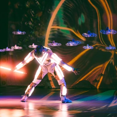 Singularity performer surrounded by synchronized illuminated drones